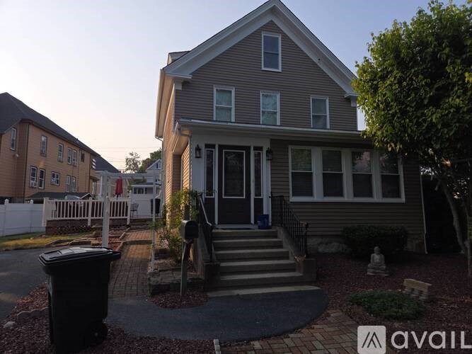 A house with a front yard and a trash can.