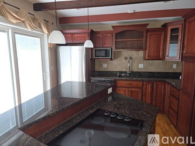 A kitchen with a granite countertop and wooden cabinets.