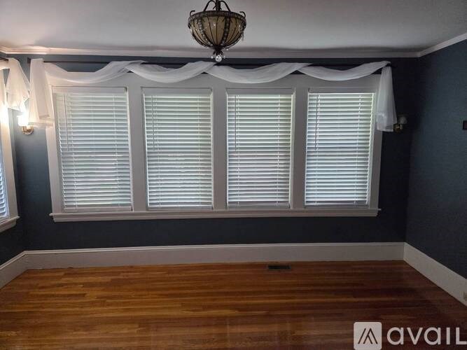 A room with wooden floors and white window blinds.
