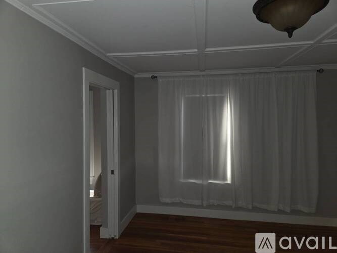 A room with a window covered by a sheer curtain.