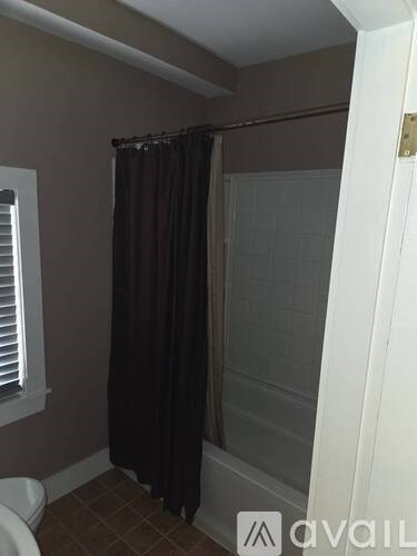 A bathroom with a toilet, a shower curtain and a shower door.