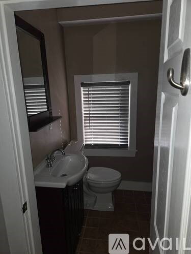 A bathroom with a toilet, sink, and window.