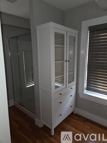 A white wardrobe with a glass door is in a room.