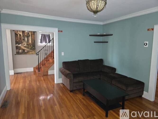 A living room with a brown couch and a chandelier.