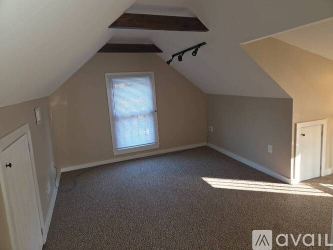 A room with a window and a carpeted floor.