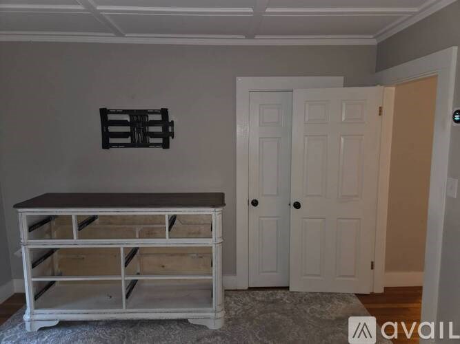 A white wooden dresser with a black top and a white door is in a room.