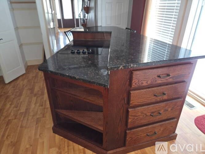 A kitchen island with a black countertop and wooden drawers.