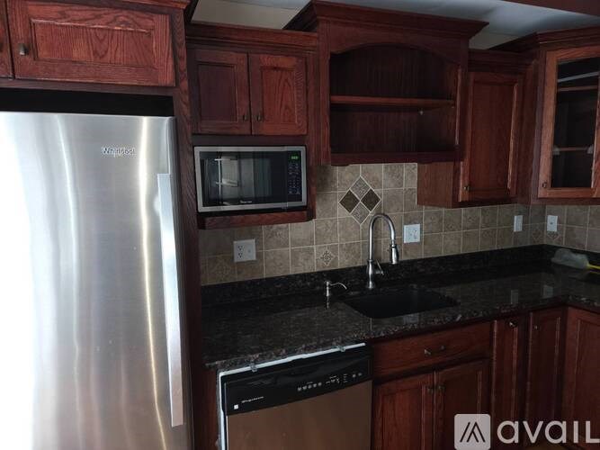 A kitchen with wooden cabinets and a stainless steel refrigerator.