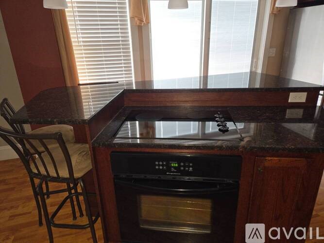 A black stove top oven with a digital display is built into a wooden cabinet.