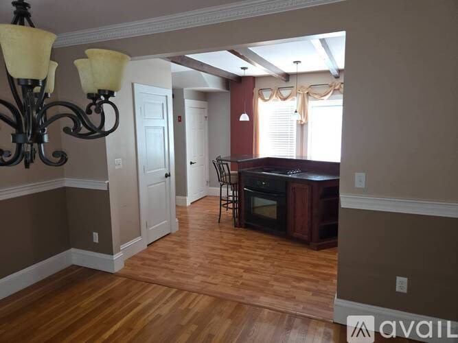 A room with a chandelier, a chair, and a piano.