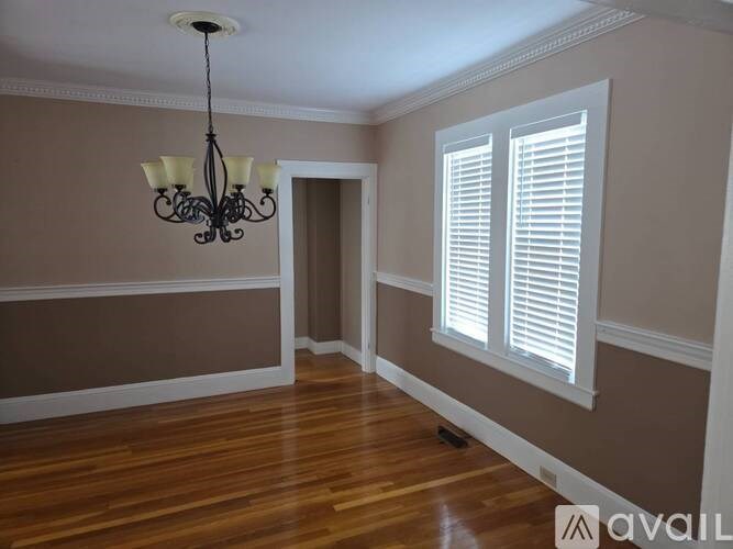 A room with a chandelier and a window with blinds.