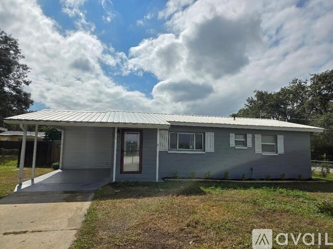 A house with a grey roof and a sign that says "AVAILABLE" in front of it.