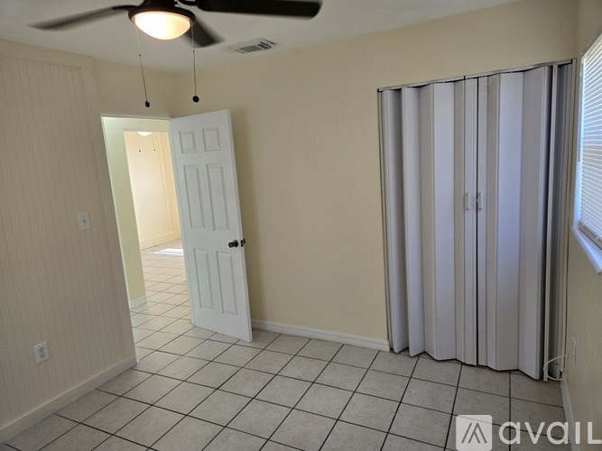 A room with a white door and a fan on the ceiling.