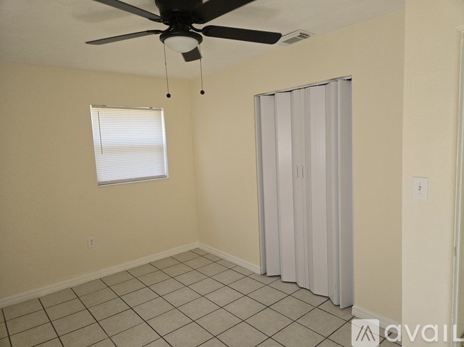 A room with a ceiling fan, a window with blinds, and a curtained door.