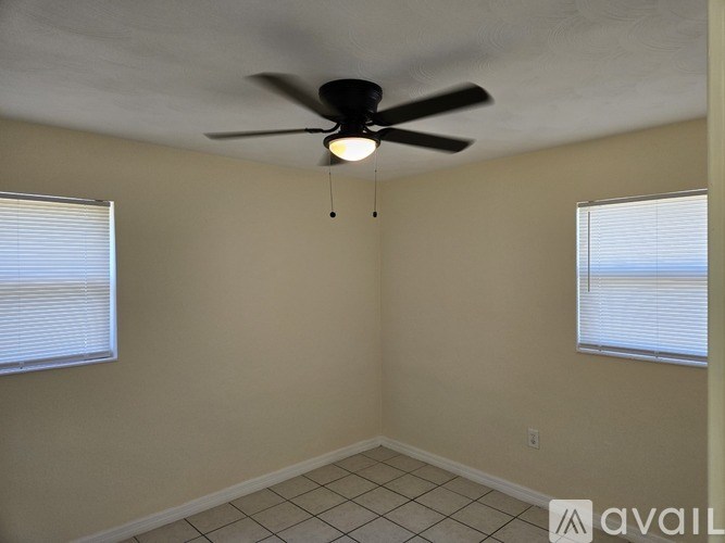 A room with a ceiling fan and two windows.