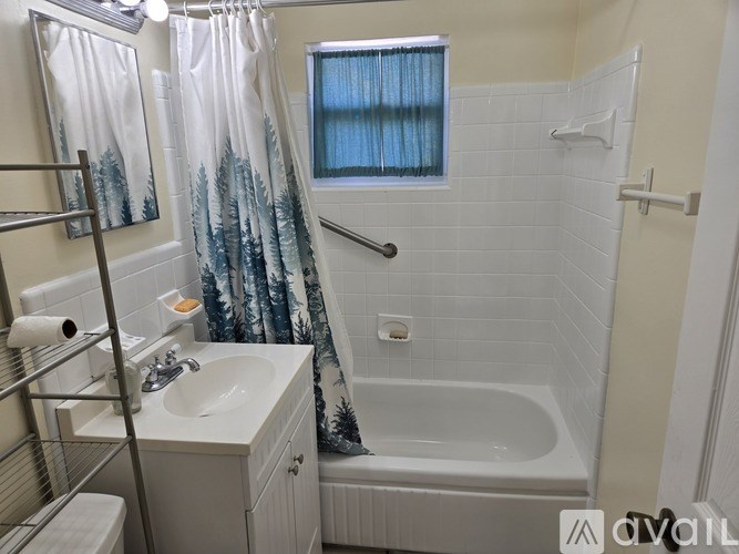 A bathroom with a white sink, a bathtub, and a window with a curtain.