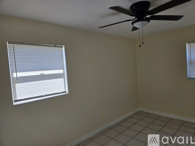 A room with a ceiling fan and a window with blinds.