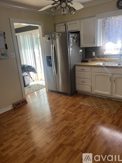 A kitchen with a refrigerator, sink, and wooden floors.