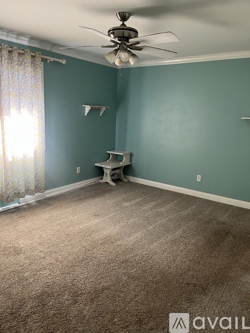 A room with a ceiling fan and a window with curtains.