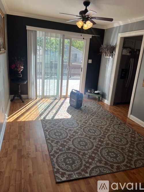 A room with a rug on the floor and a ceiling fan above.