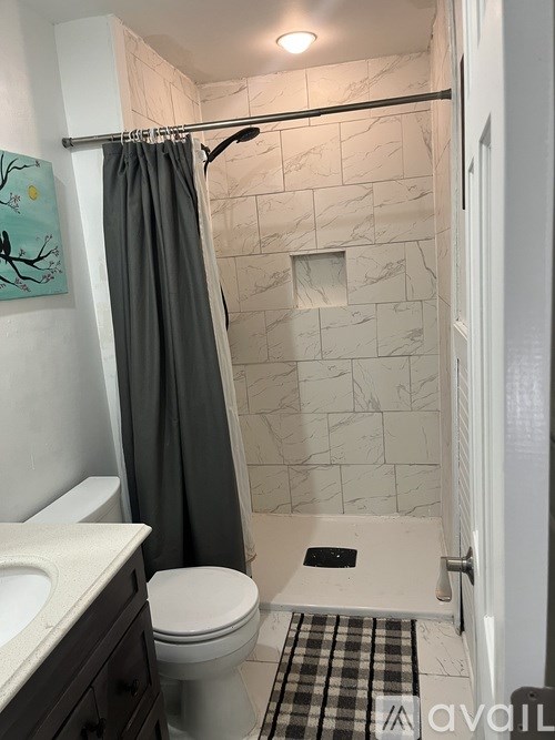 A bathroom with a toilet, sink, and shower.