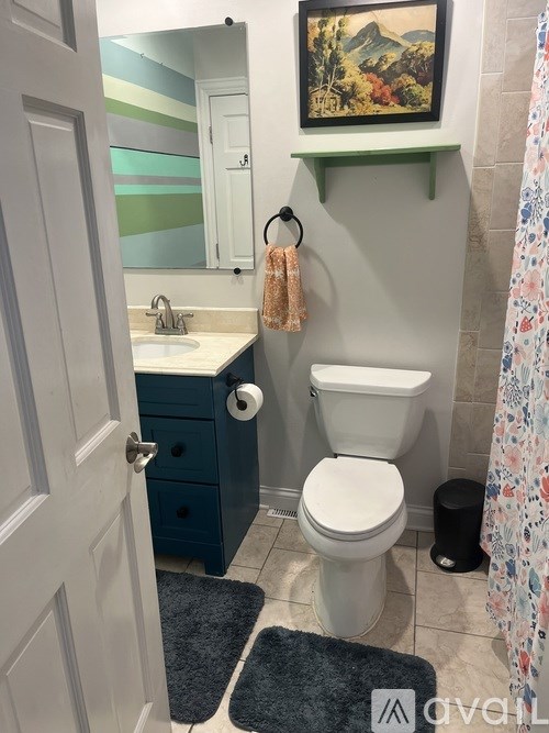 A bathroom with a toilet, sink, and a painting on the wall.