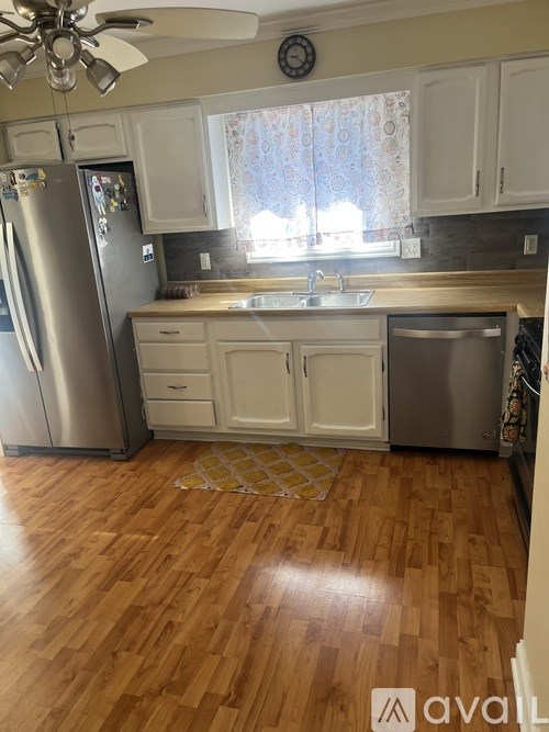 A kitchen with wooden floors and white cabinets.