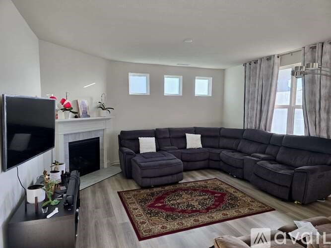 A living room with a grey sectional sofa, a fireplace, and a rug.