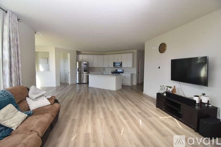 A living room with a brown couch and a flat screen TV mounted on the wall.