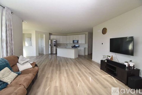 A living room with a brown couch and a flat screen TV mounted on the wall.