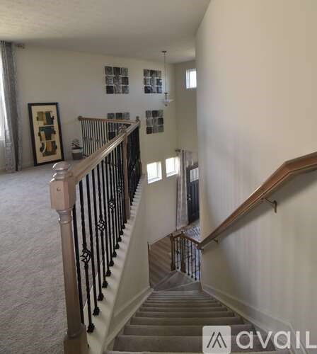A staircase with a black railing and a wooden handrail.
