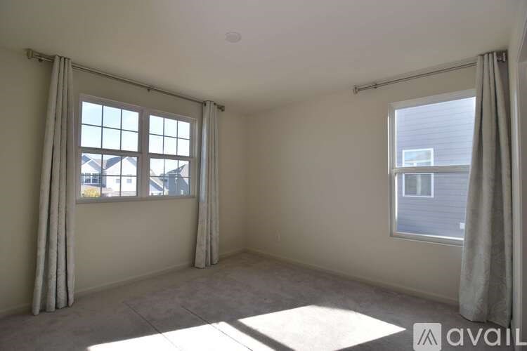 A room with two windows and a view of a building outside.