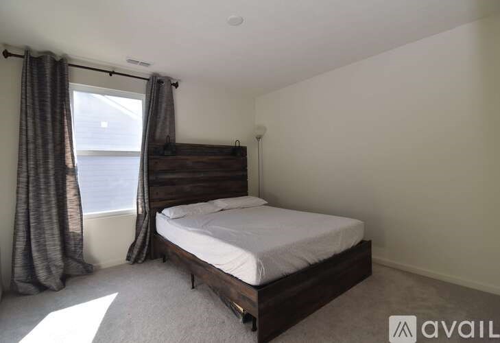 A bedroom with a bed, window, and curtains.