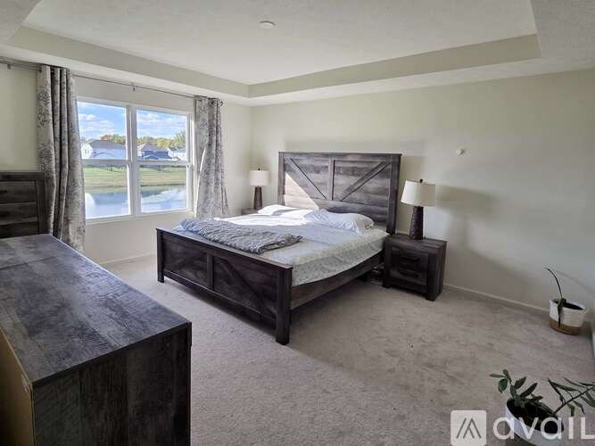 A bedroom with a large bed and a window overlooking a body of water.
