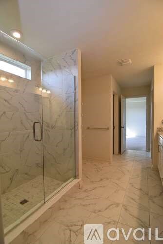 A bathroom with marble flooring and a walk-in shower.