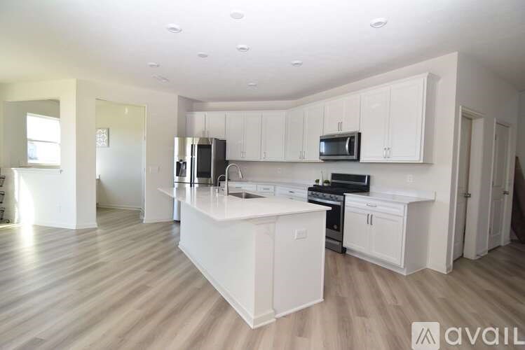 A kitchen with white cabinets and a wooden floor.