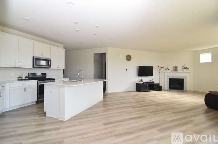 A spacious living room with a fireplace and a kitchen area with white cabinets.