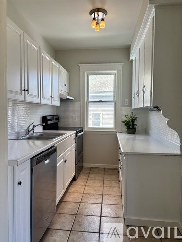 A kitchen with white cabinets and a tiled floor.