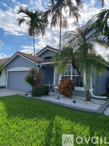 A house with a driveway and palm trees in front.