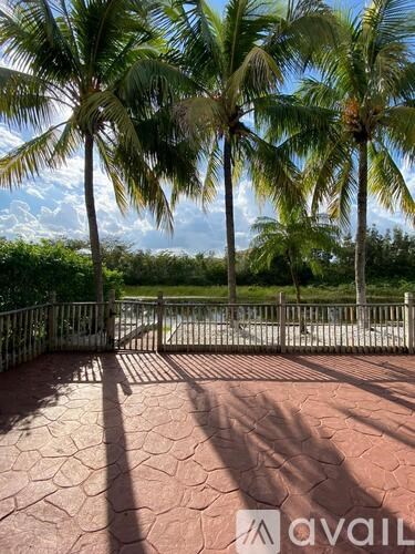 A patio with a gate and palm trees in the background.