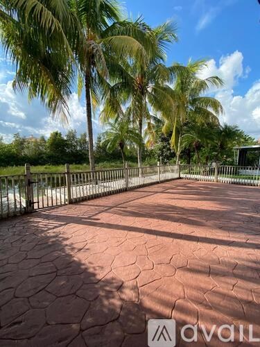 A sunny day at the beach with palm trees and a fence.