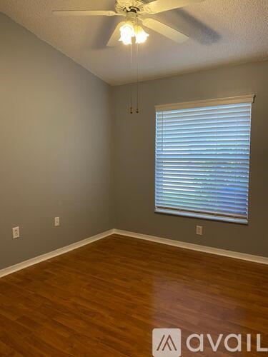 A room with a ceiling fan and a window with blinds.