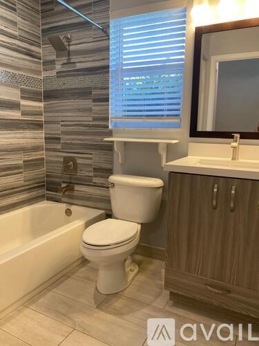 A white toilet in a bathroom with a wooden cabinet and a bathtub.