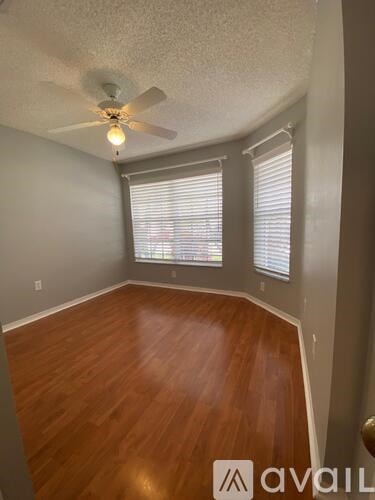 A room with a ceiling fan and wooden flooring.