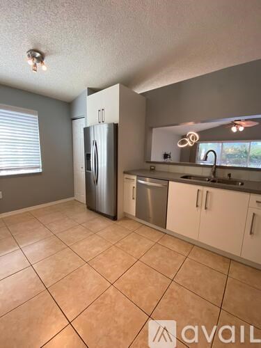 A kitchen with tile flooring and a refrigerator.