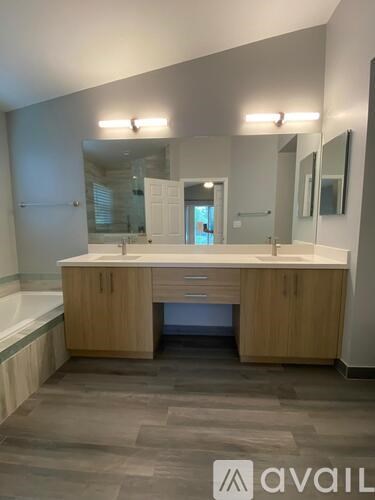 A bathroom with a large mirror and wooden cabinets.