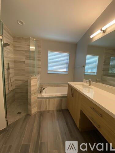 A bathroom with a tub, sink, and mirror.