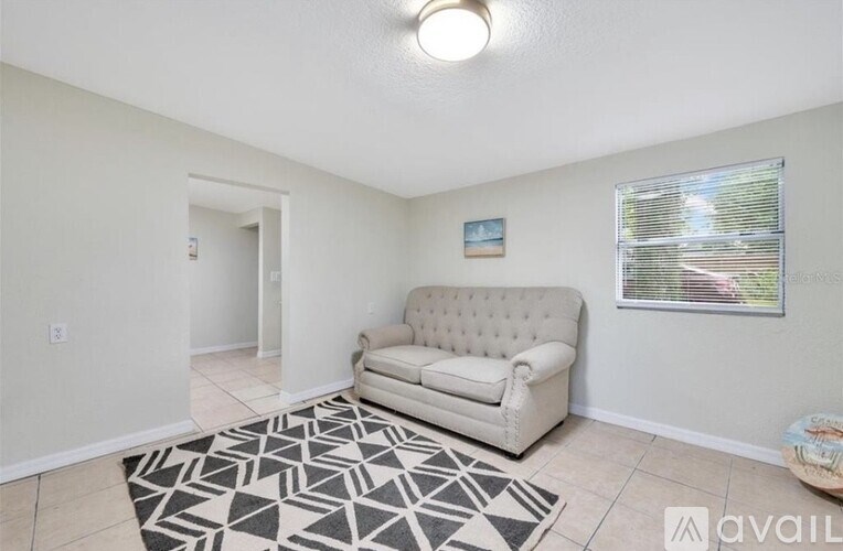 A living room with a white couch and a patterned rug.