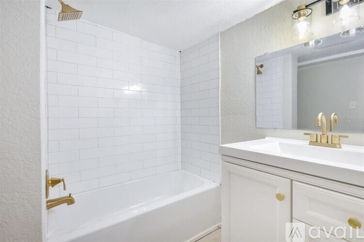 A white bathroom with a tub, sink, and mirror.