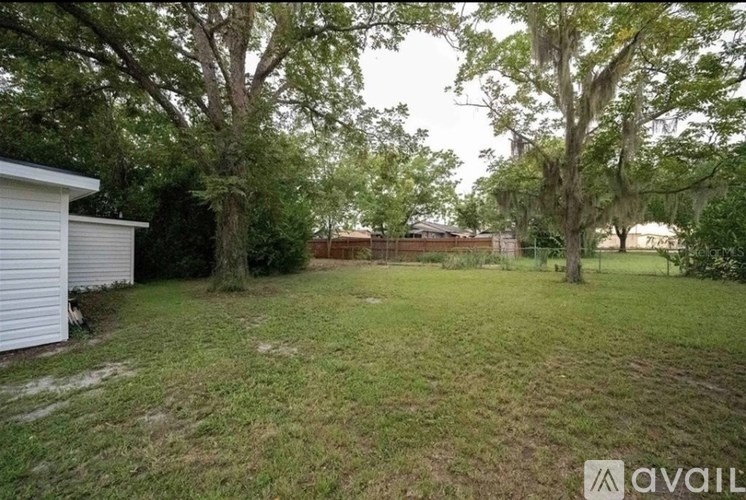 A backyard with a white fence and trees.